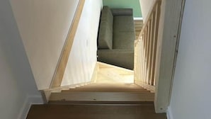 A narrow stairway leading to a lofted room with a green wall and a cushioned seating area. - Les Coteaux III (Gérardmer)