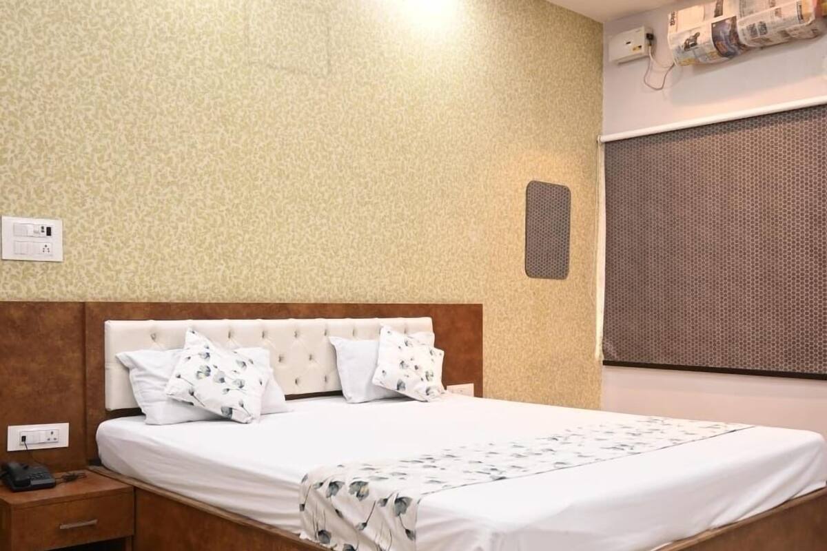 A modern bedroom with a large bed, wooden headboard, and a nightstand.