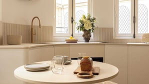 A modern kitchen with a round dining table, a built-in bench, and a decorative wall piece. - Luxurious Astorg Residence (Paris)