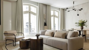 A modern living room with a beige sofa, a round coffee table, and a minimalist chandelier. - Luxurious Astorg Residence (Paris)