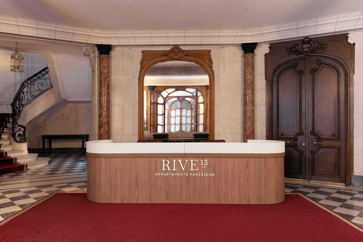 A reception area with a check-in counter, a staircase, and a large wooden door.
