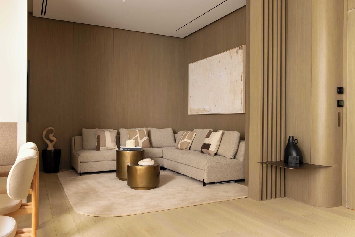 A modern living room with a sectional sofa, round coffee tables, and a minimalist decor style.