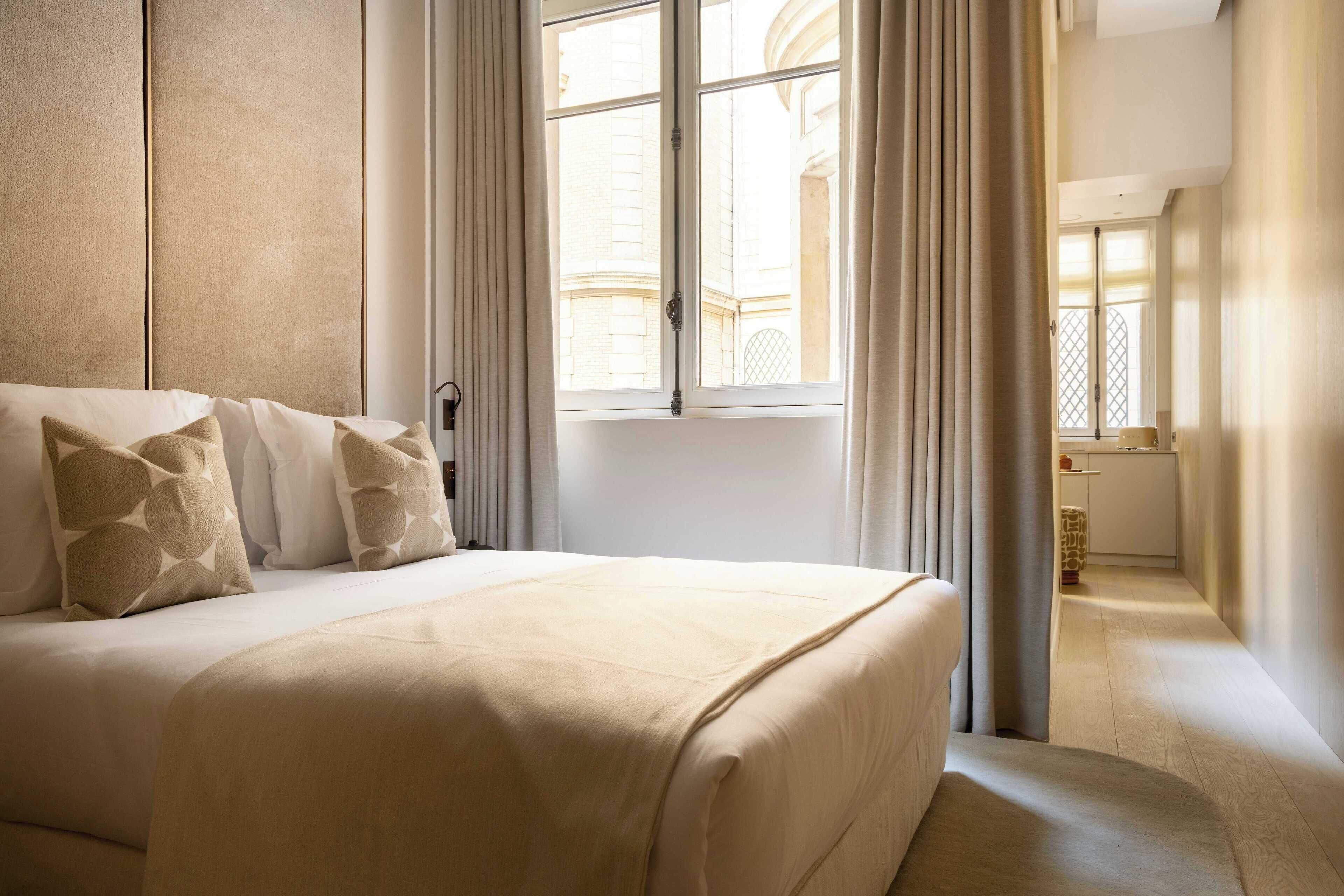 Une chambre d’hôtel avec un grand lit, une vue sur l’extérieur et une salle de bain visible par une porte ouverte.