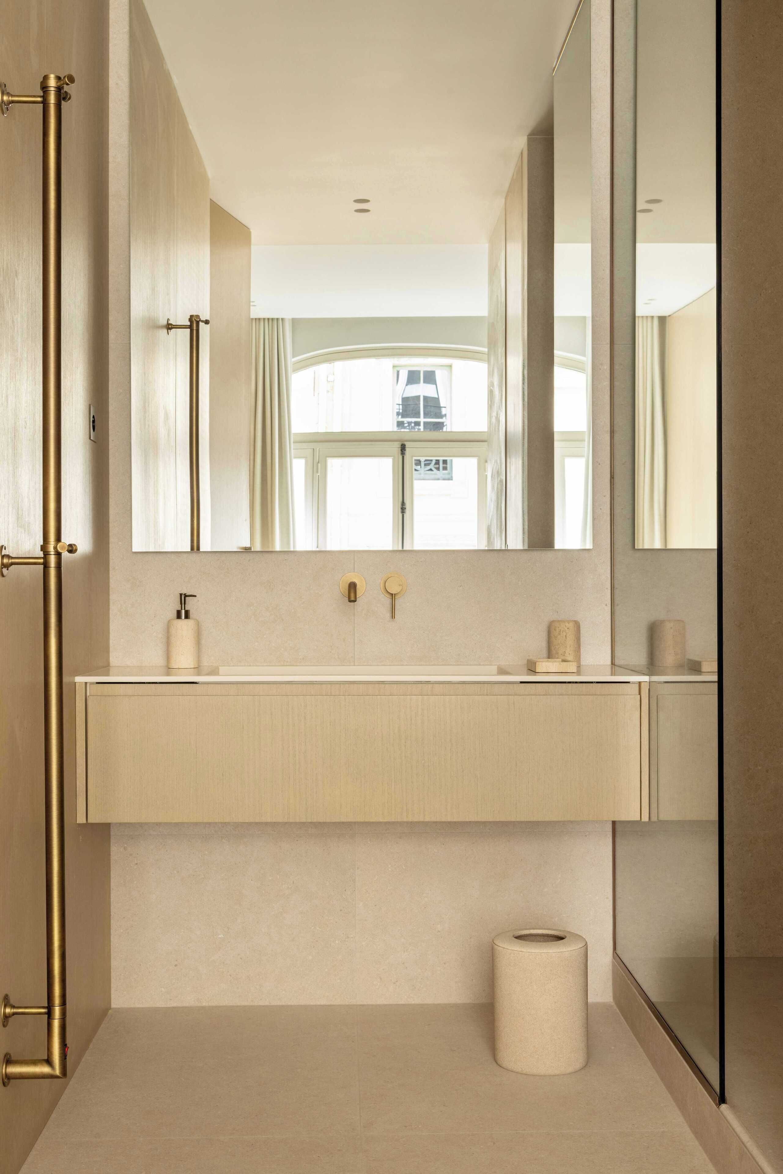 Une salle de bain moderne avec un grand miroir, un lavabo beige et un porte-rouleau de papier toilette.