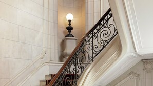 A grand staircase with ornate metal railings and red carpeted steps. - Luxurious Astorg Residence (Paris)