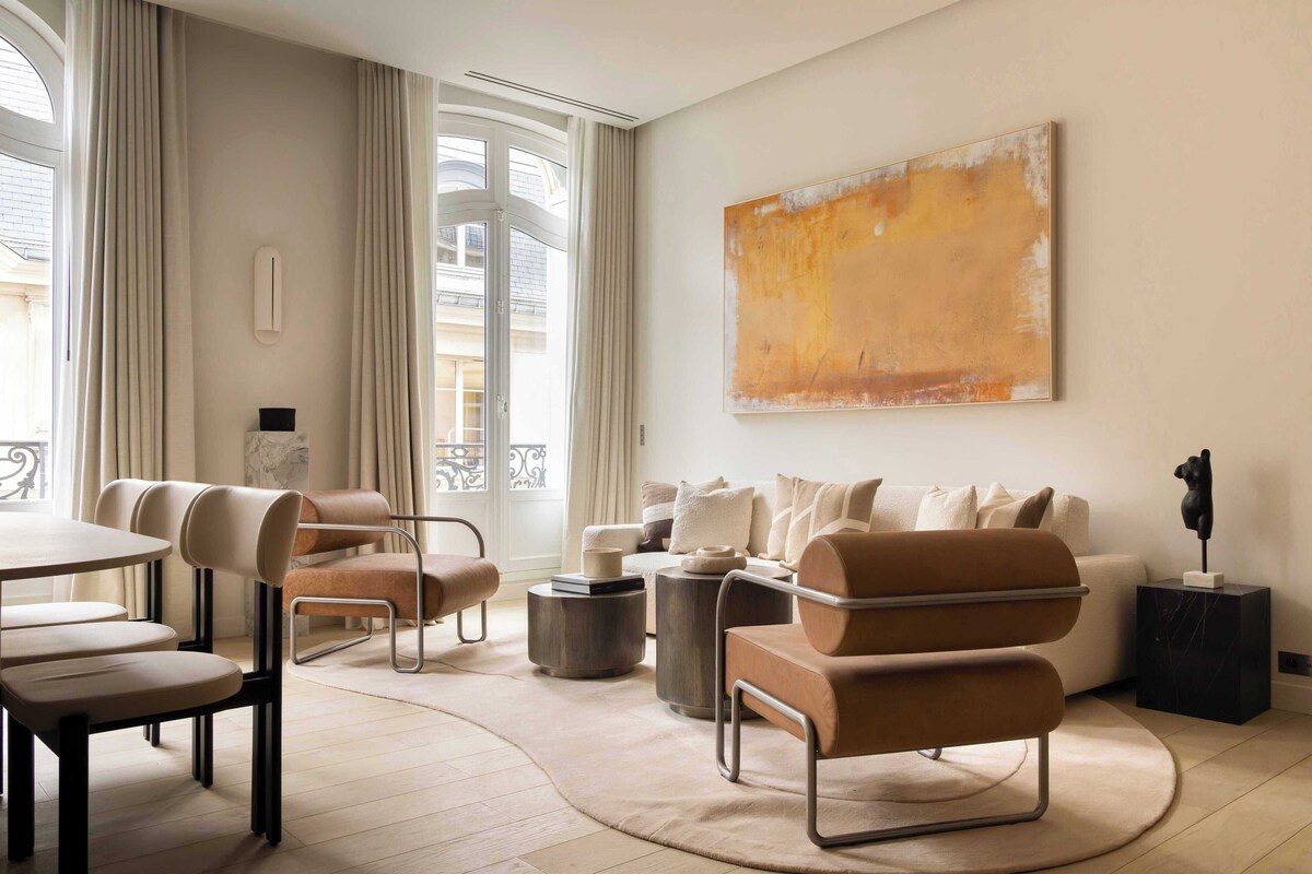 A modern living room with a sofa, chairs, a coffee table, and a large abstract painting on the wall.