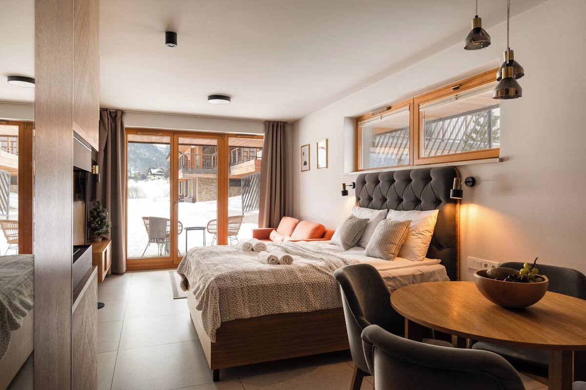 Une chambre moderne avec un grand lit, une table à manger et une vue sur un paysage enneigé.