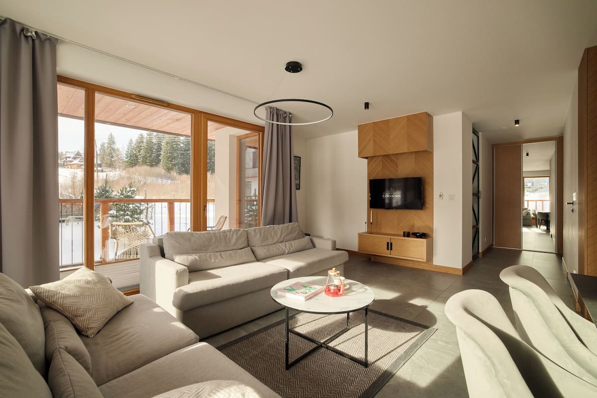 Un salon moderne avec un canapé, une table basse et un téléviseur.