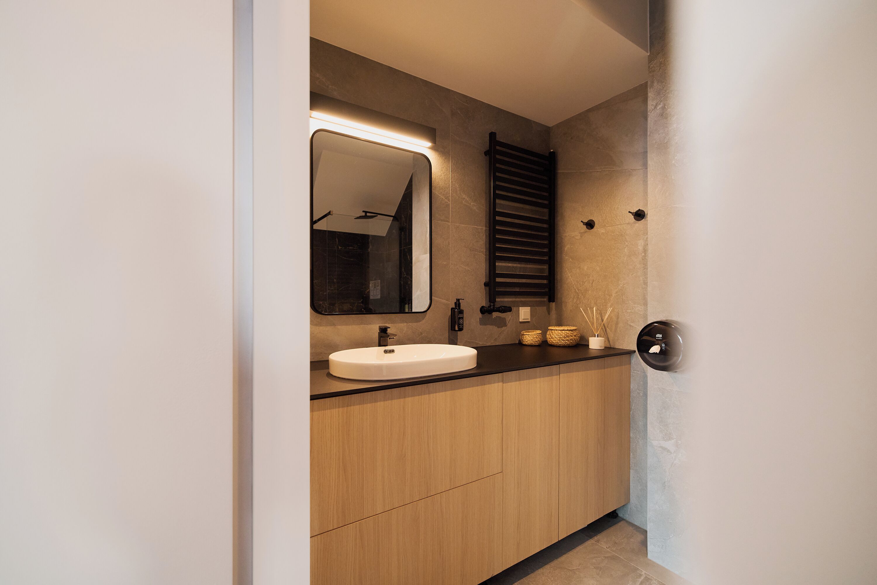 Een moderne badkamer met een grote spiegel, een wastafel en een handdoekhouder.
