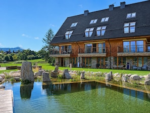 A two-story house with a large deck and a pond.