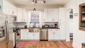 A modern kitchen with white cabinets, stainless steel appliances, a wooden countertop, and a window with a view. - Minutes to Hospital, Cozy 3BR w/ Game Room, Family-Friendly (Columbus)