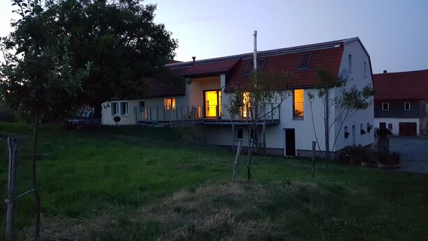 A two-story house with a red roof, a balcony, and a well-maintained lawn. - Gut Belgerhof Steinbach Holiday Apartment (Steinbach)