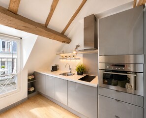 A modern kitchen with a stainless steel refrigerator, double oven, and a built-in stove. - 1531 Bourgeois (Paris)
