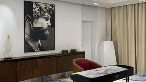 Un salon moderne agrémenté d’un grand lustre, d’un tableau accroché au mur, d’un violon posé sur une console et d’une table basse en marbre.