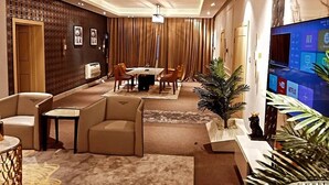 Un hall d’hôtel moderne comprenant un espace repas, des sièges, un téléviseur et une plante décorative.