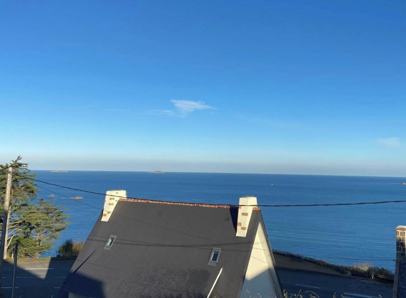A view from a rooftop with a clear blue sky and the ocean in the distance.