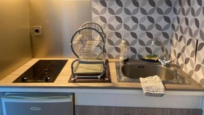 Une cuisine compacte équipée d’un four à micro-ondes, d’un évier et d’un petit lave-vaisselle.