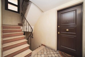 A staircase with a handrail, a brown door with a gold handle, and a small window above the door. - BuddyRent - Trevi Fountain - Roma - 3 ospiti (Roma)