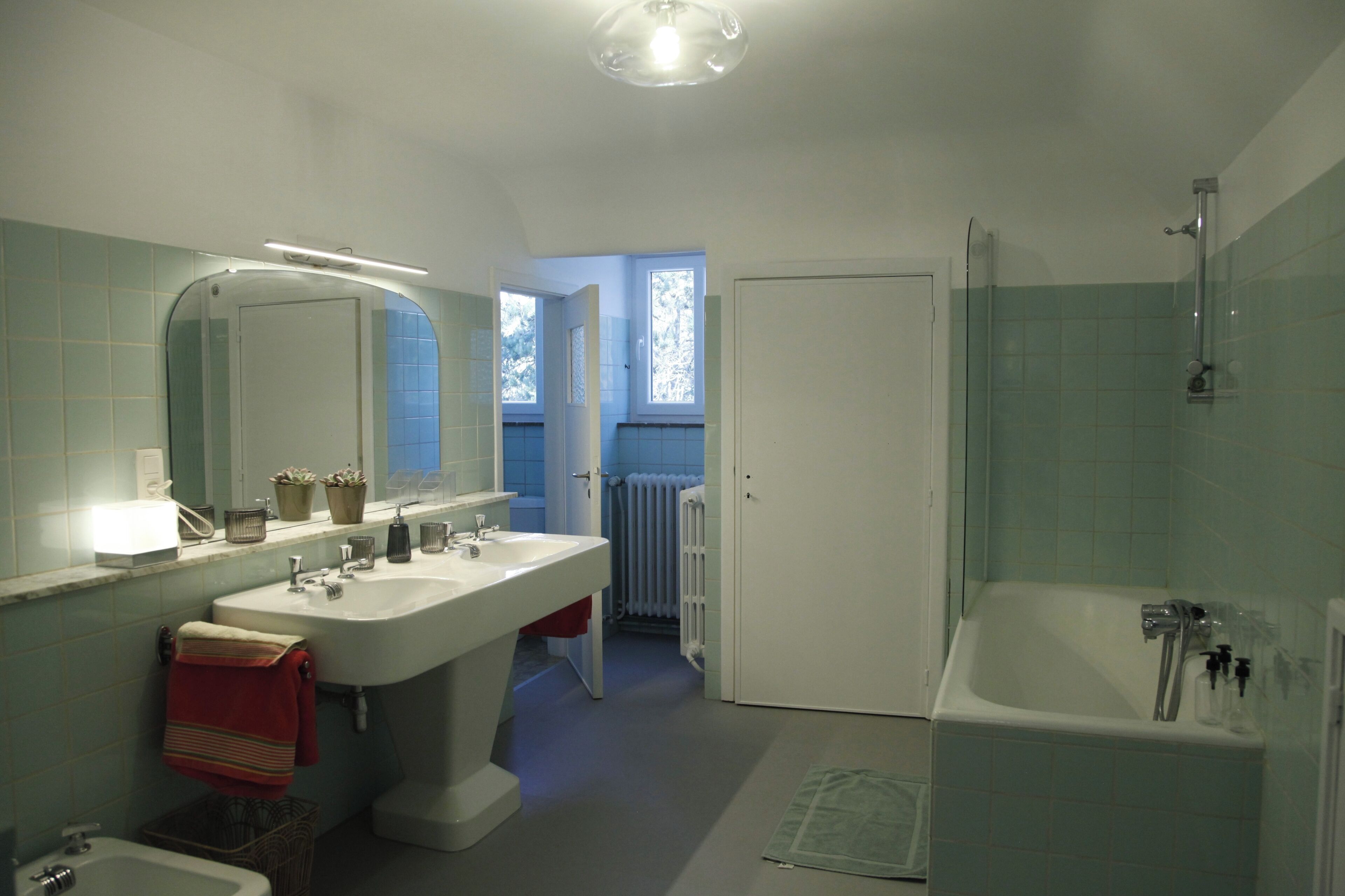 A bathroom with a double sink, a large mirror, a bathtub, and a shower.