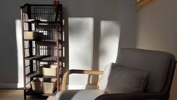 Ein Zimmer mit einem grau gepolsterten Sessel und einem Korbschrank an der Wand.