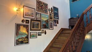 A staircase with wooden railings and a wall decorated with various framed artworks. - Aux étangs fleuris (Rochefort)