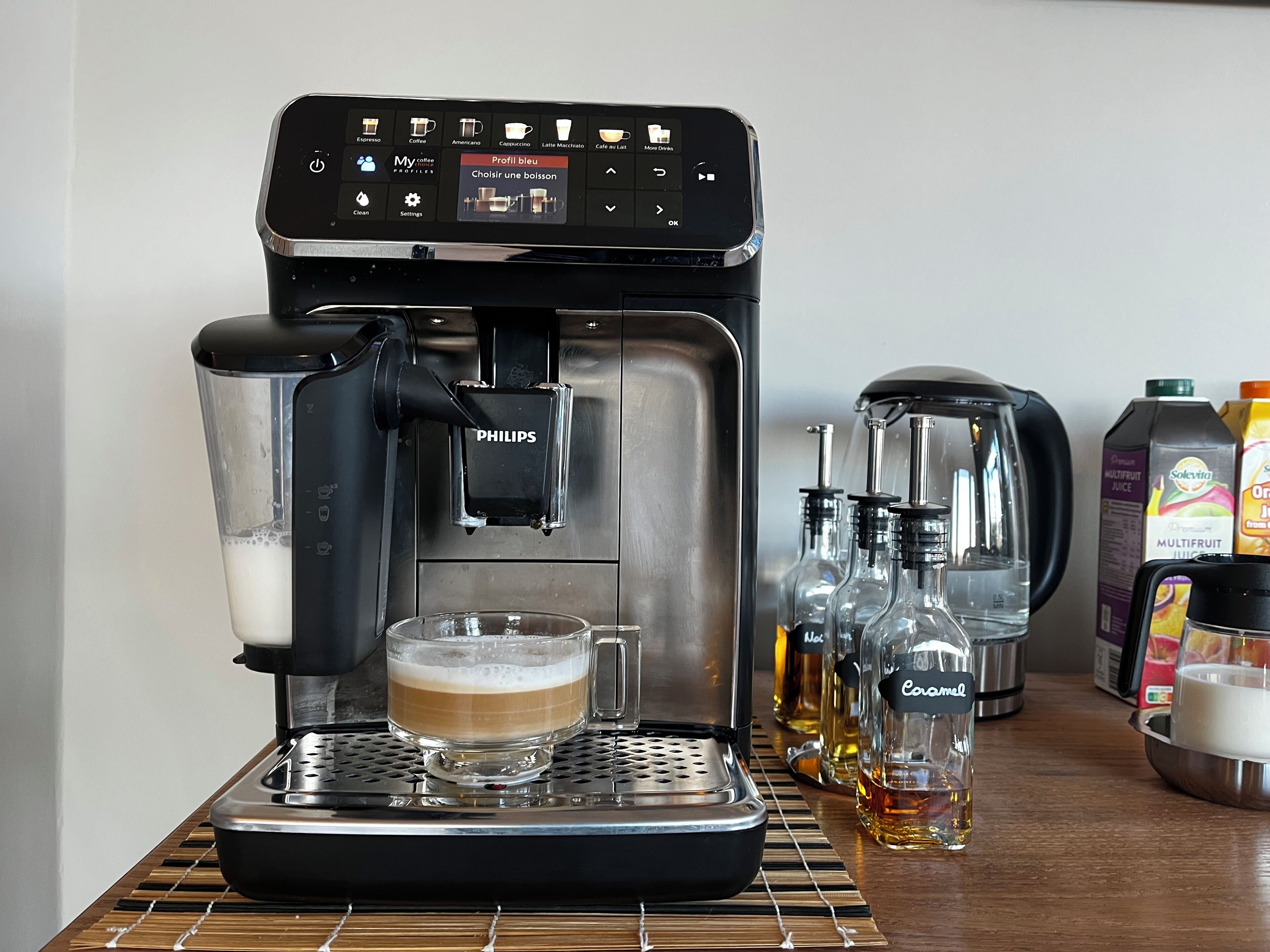 A coffee machine with a glass cup on the drip tray, a coffee pod dispenser, and a coffee maker.