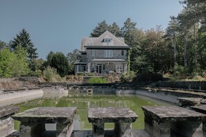 A stone building with a large pond in front, surrounded by trees. - Aux étangs fleuris (Rochefort)