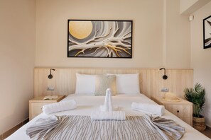A hotel room with a large bed, a nightstand, a wall-mounted artwork, a bedside lamp, a plant, and a woven basket.
