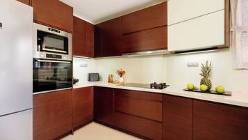 A modern kitchen with built-in appliances, wooden cabinetry, and a white countertop.