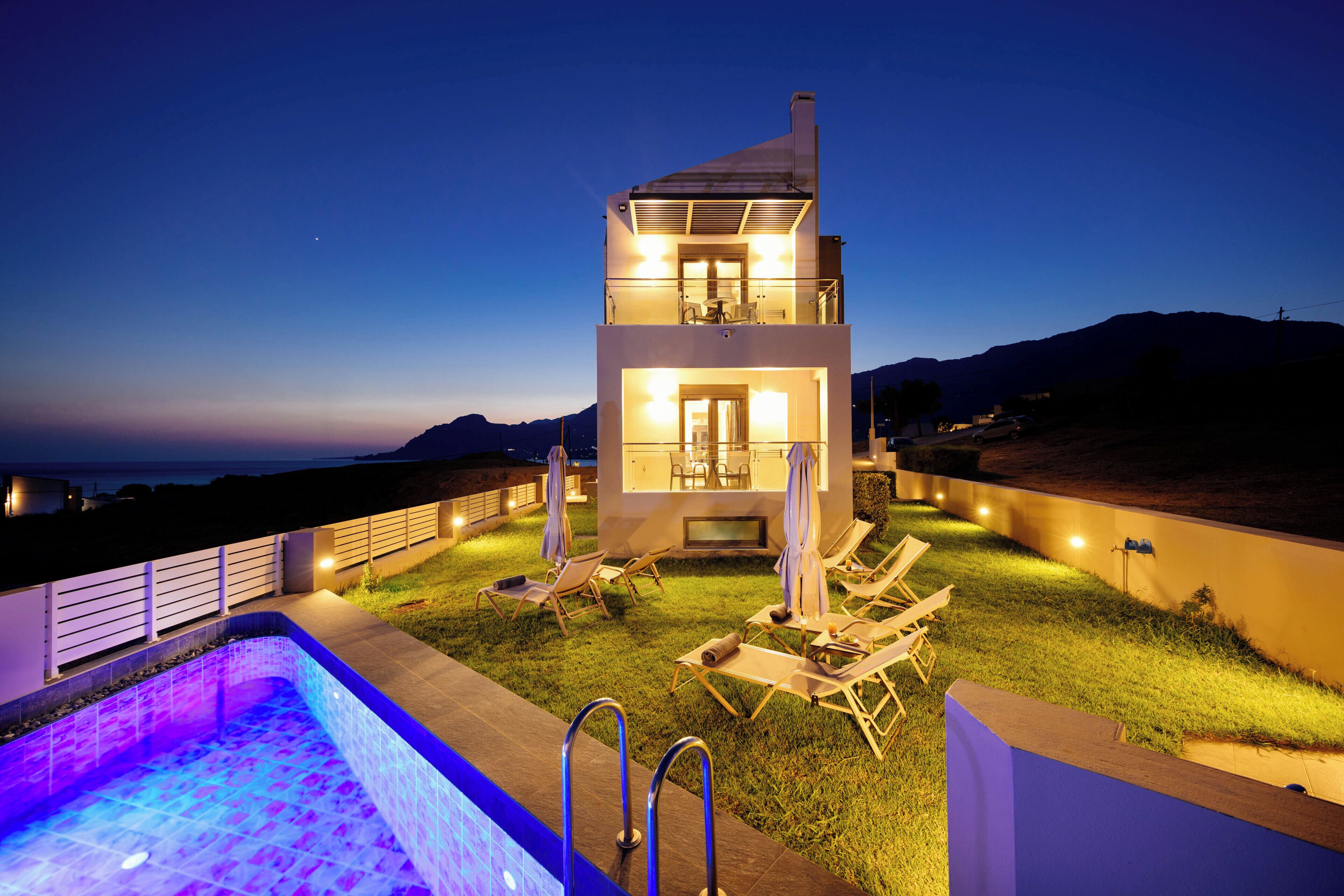 Ein modernes, zweistöckiges Gebäude mit Pool, Außenbereich und Blick auf die Berge.