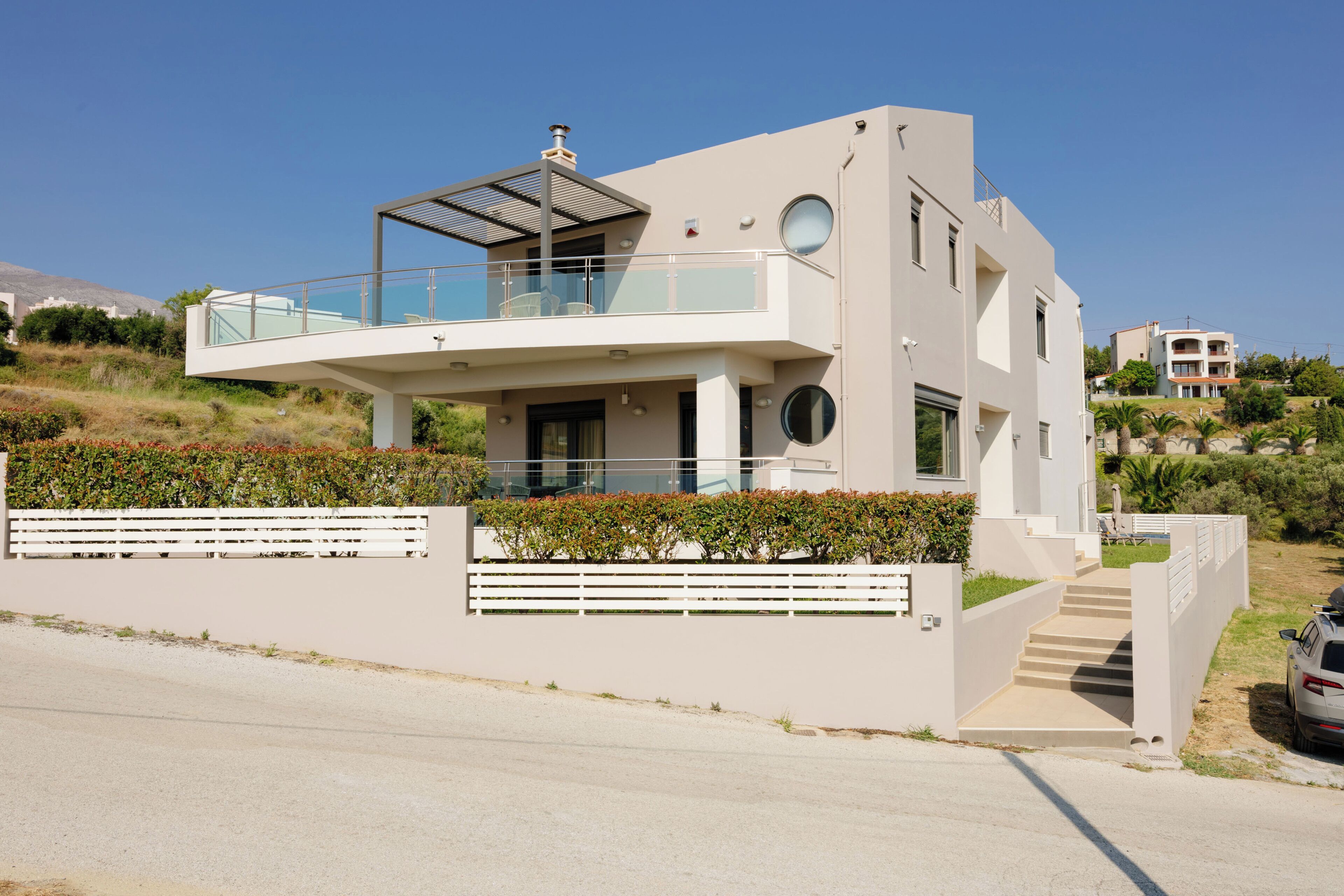 Una casa moderna de dos pisos con balcón, garaje y entrada para vehículos.