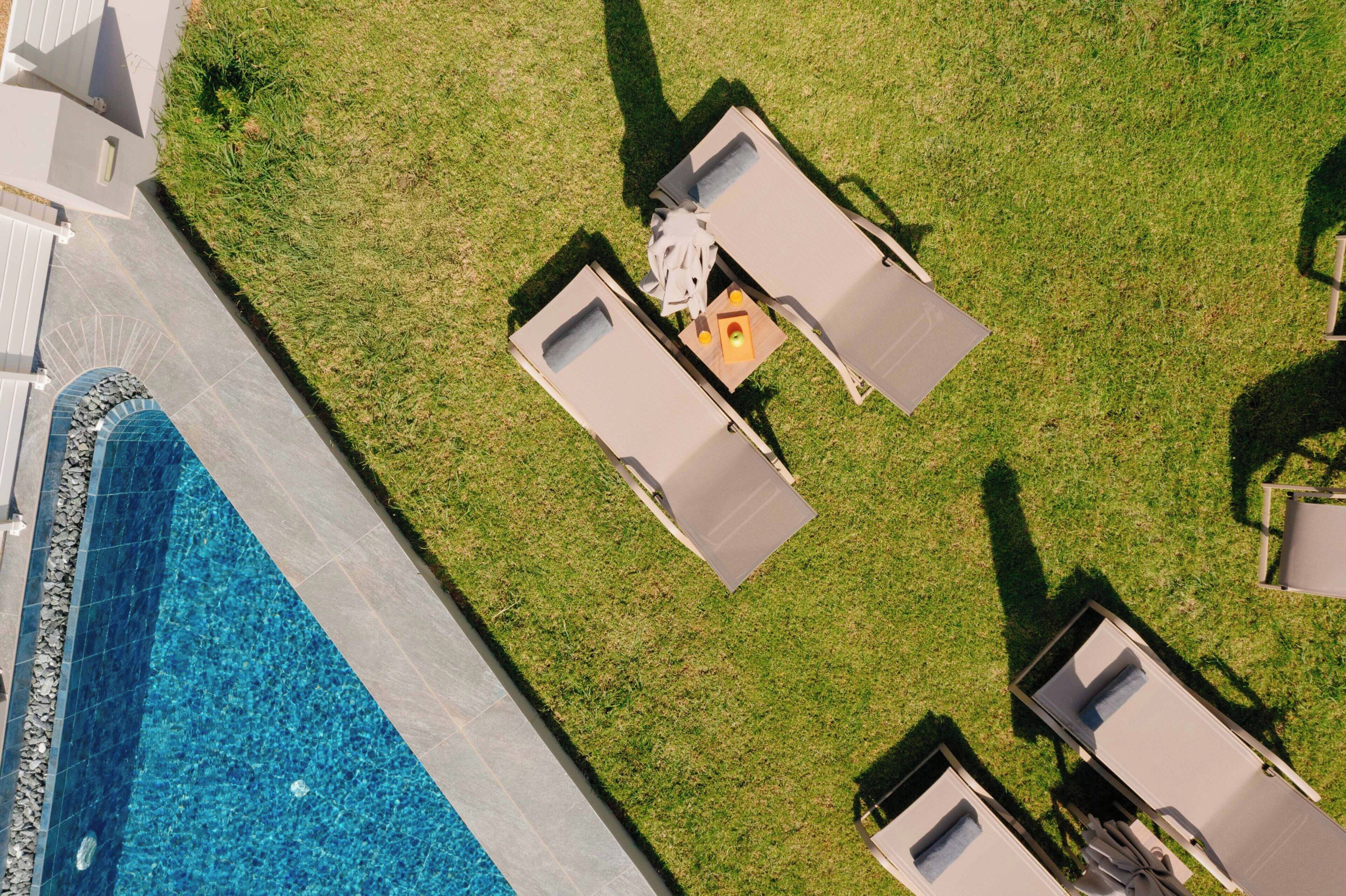 Vista aérea de un área junto a la piscina con sillones de descanso y una pequeña mesa con bebidas.