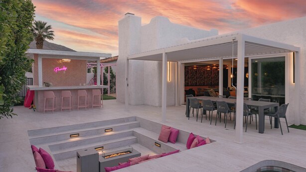 Un patio exterior moderno con barra, asientos y una piscina.