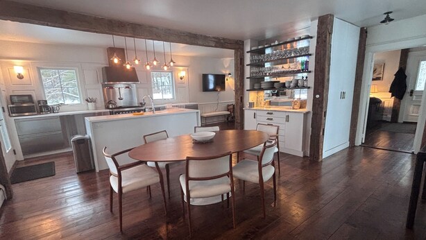 Una cocina moderna con suelo de madera, una isla central e iluminación colgante.