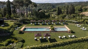 A pool area with lounge chairs and umbrellas, surrounded by well-maintained lawns and trees. - VILLA ARTIUM - Twenty Bedroom Villa, Sleeps 37 (Firenze)