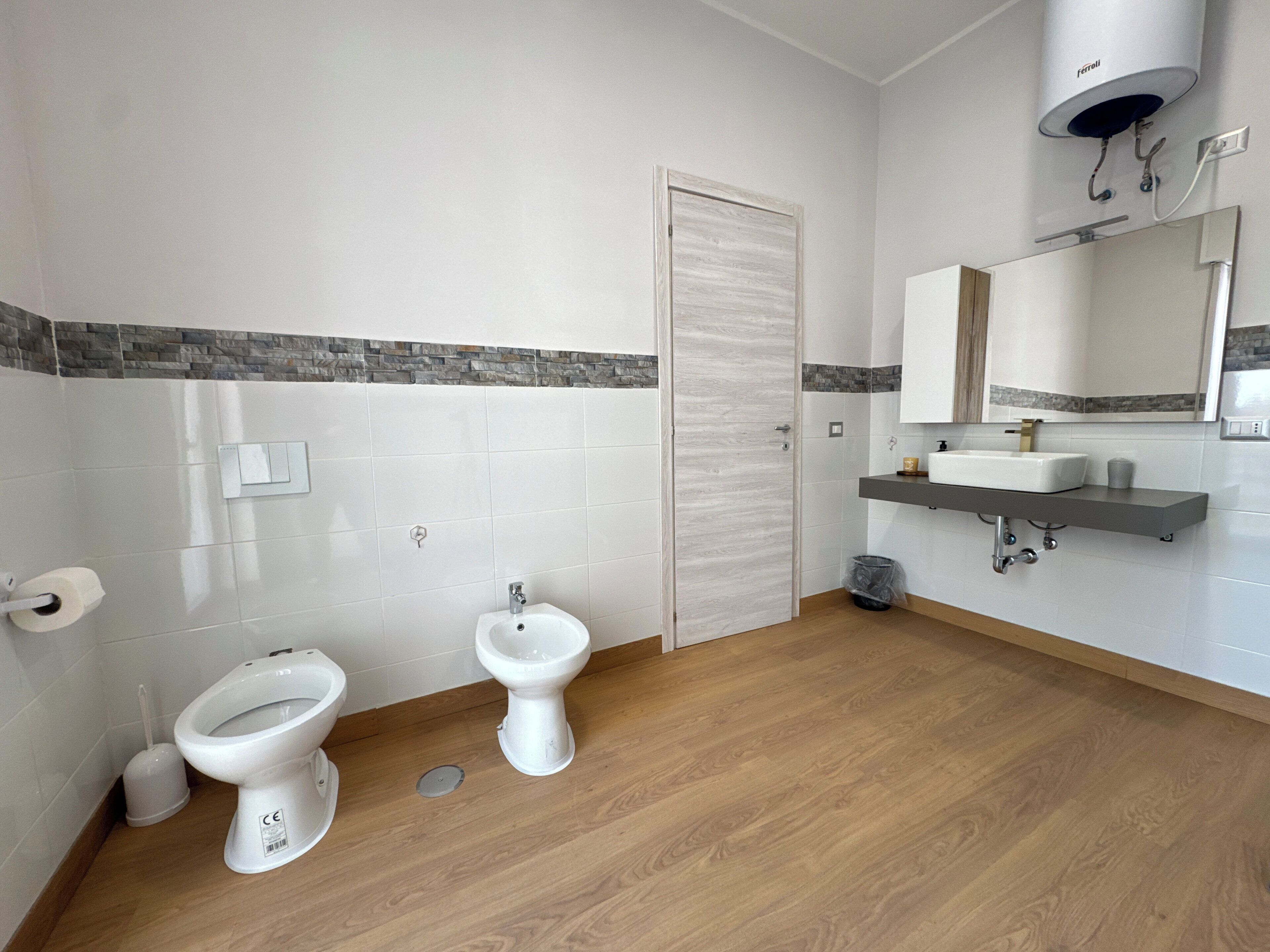Une salle de bain avec deux toilettes, un lavabo, un miroir et une douche.