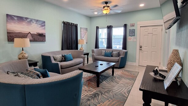 A living room with a sofa, armchairs, a coffee table, and a TV. - Coral Bungalow (Galveston)