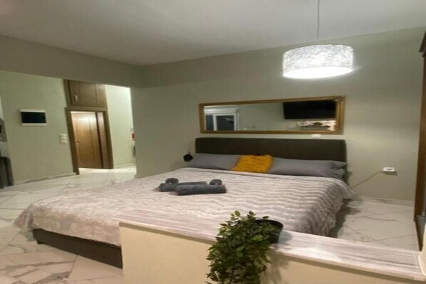 Une chambre à coucher avec un lit, une table de chevet, un miroir et une plante en pot.