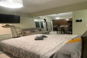 Une chambre avec un grand lit, un canapé et un coin repas à l’arrière-plan.