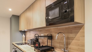 A modern kitchen with a stainless steel sink, a kettle, a coffee maker, and a microwave. - 2A Ruby Street (London)