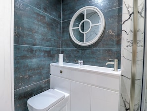 A modern bathroom with a white toilet, a sink with a mirror, and a shower area.