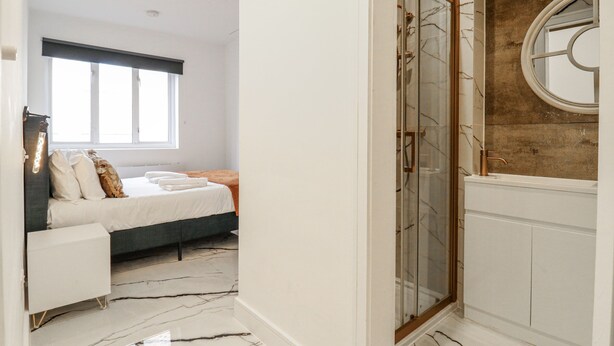 A bedroom with a bed, bedside table, and a window. - 2A Ruby Street (London)