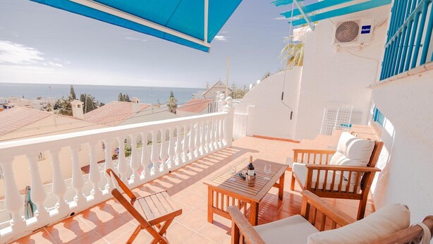 A balcony with a view of the sea, wooden furniture, and a ceiling fan. - Apartment 'Melina' with Sea View, Wi-Fi and Air Conditioning (Cala del Moral)