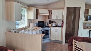 A compact kitchen with a stove, microwave, and cabinets. - 2bed-cabin Sleeps 4, Wifi, Free Parking, Sea Views (Bembridge)