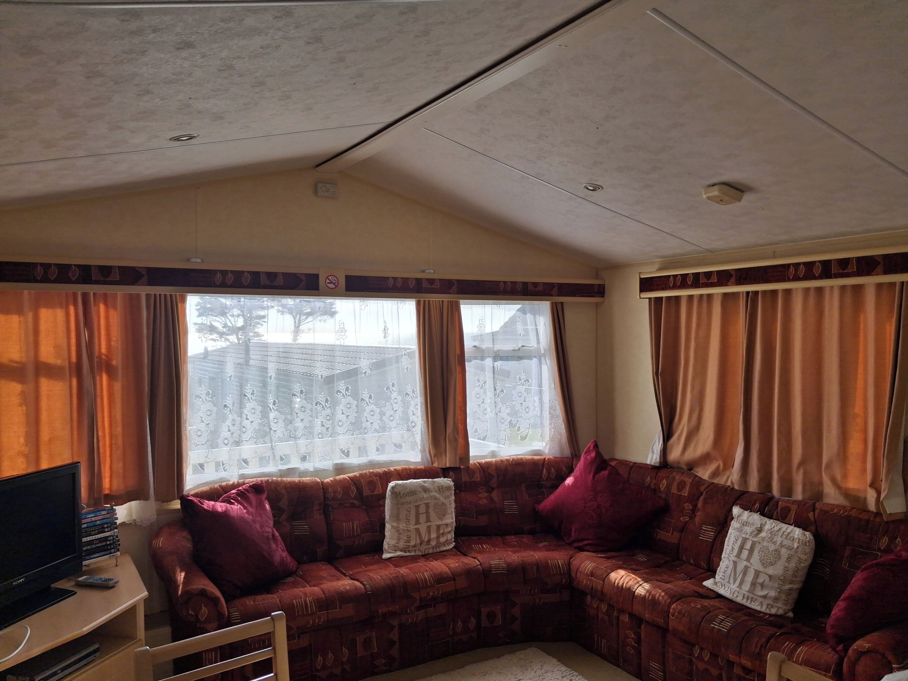 A living room with a sofa, a TV, and a window with curtains.