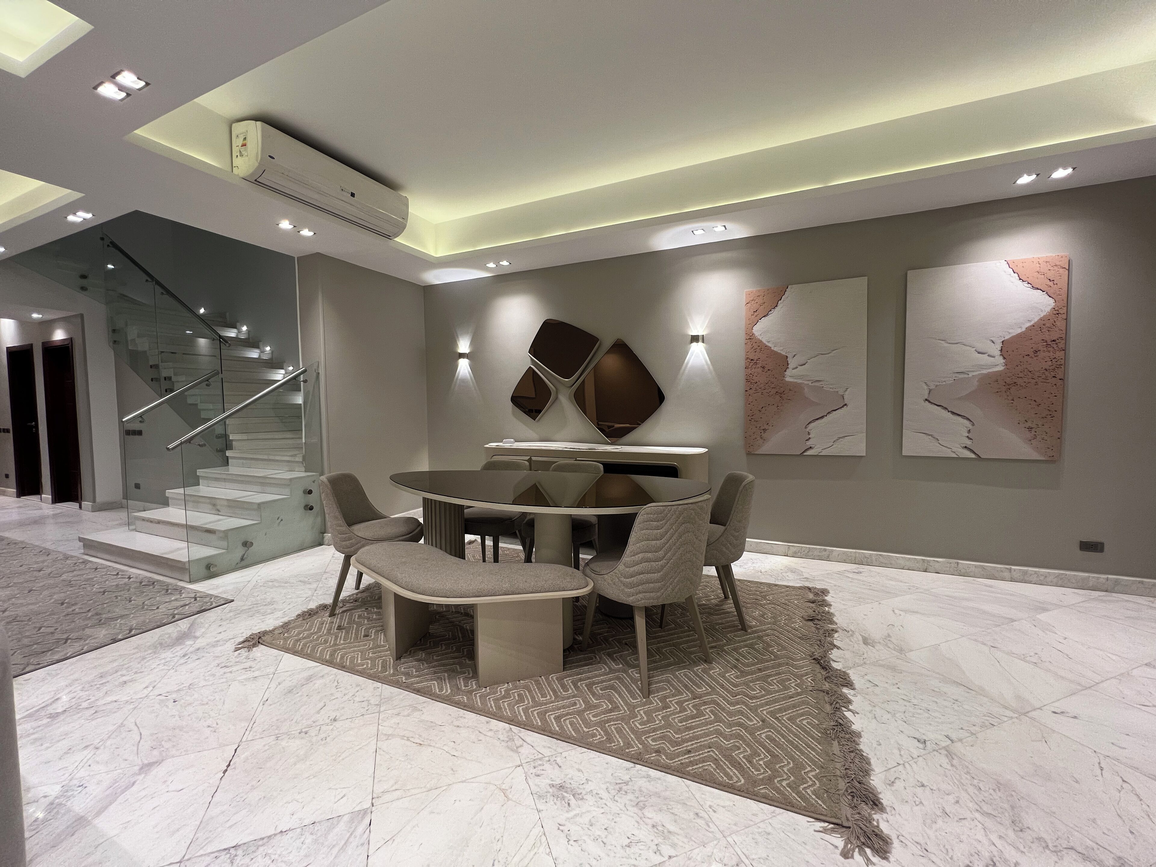 A modern interior with a dining area, staircase, and artwork.
