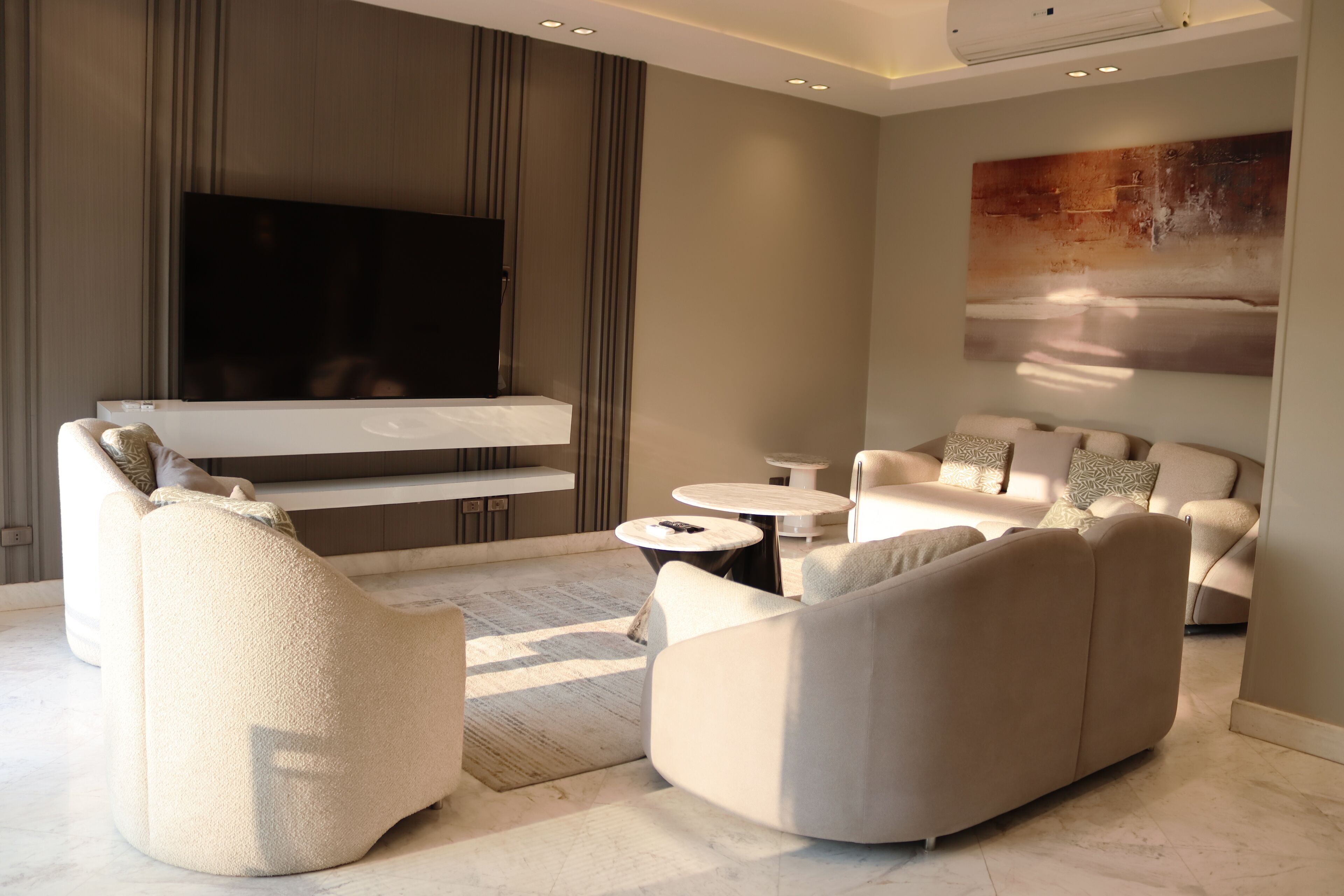 Een moderne woonkamer met een grote flatscreen televisie, comfortabele zithoek en een minimalistisch design.