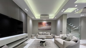 A modern living room with a large flat-screen TV, a sofa set, a coffee table, and a patterned rug. - ALSAWAH 5-Bedroom Villa with Private Pool  Palm Hills Sheikh Zayed (6th of October City)