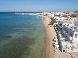 En la playa, arena blanca, sillas reclinables de playa, sombrillas