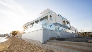 A modern building with a glass facade, located near a beach. - scirocco boutique eco hotel (Torre Pali)